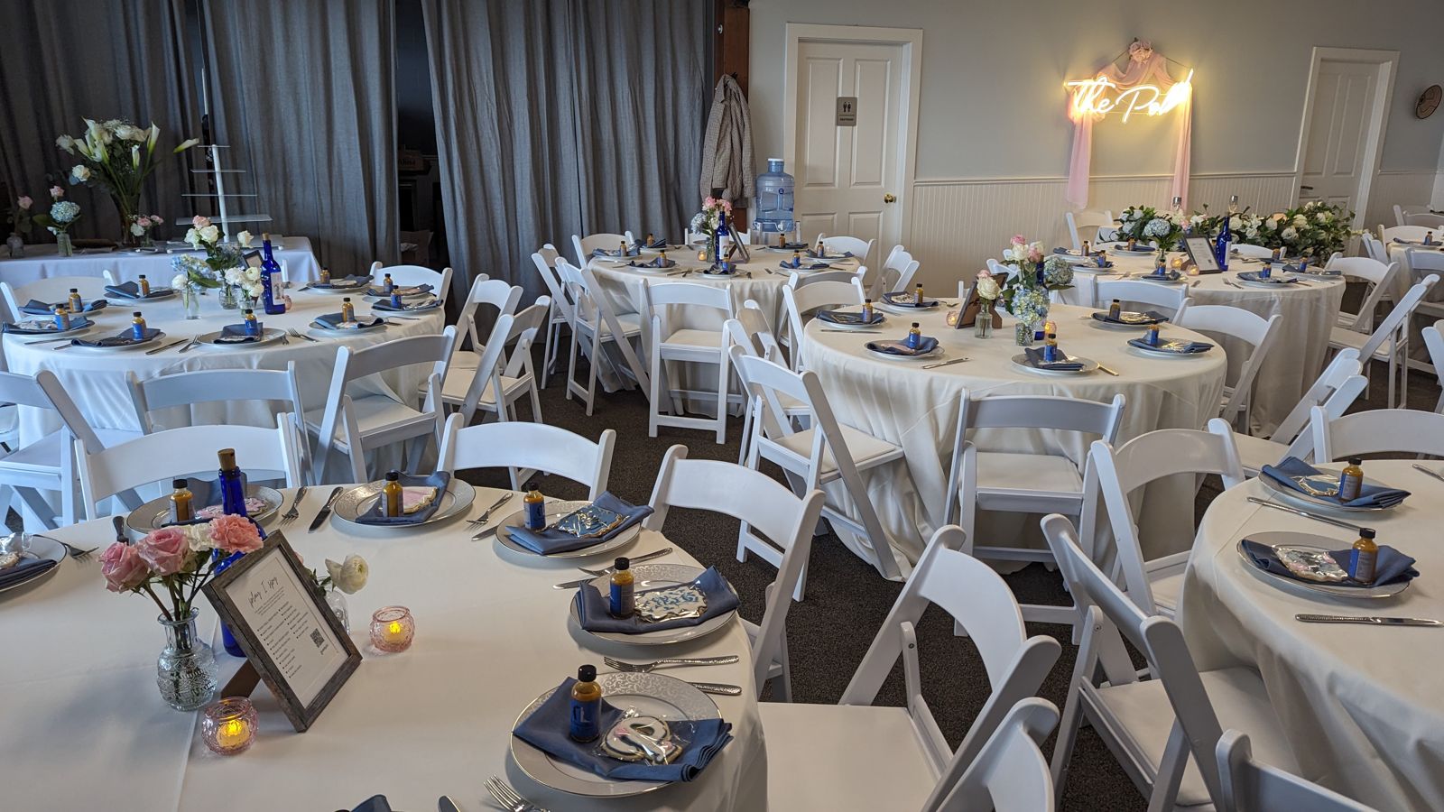 Indoor event space set with round tables and linens for a seated dinner at Living Well Event Center